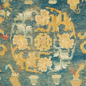 May include: A vintage rug with a blue background and intricate floral patterns in shades of yellow, red, and white.