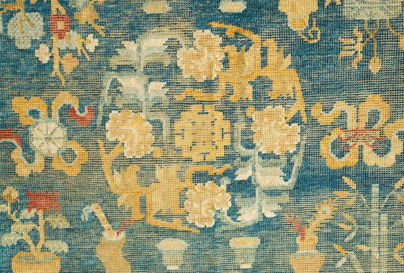 May include: A vintage rug with a blue background and intricate floral patterns in shades of yellow, red, and white.