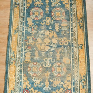 May include: A vintage rug with a blue background and a yellow border. The rug features a repeating pattern of stylized flowers and geometric shapes.