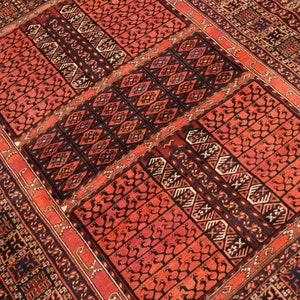 May include: A red, black, and white patterned rug with a geometric design. The rug has a traditional Persian style.