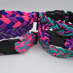 May include: A collection of braided paracord collars featuring black plastic side-release buckles and metal D-rings. The collars display various color combinations including bright pink, royal blue, purple, teal, and black with reflective accents.