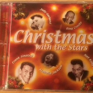May include: A red CD case with a gold background featuring a collage of five singers: Judy Garland, Bing Crosby, Frank Sinatra, Mahalia Jackson, and Nat King Cole. The text "Christmas with the Stars" is printed in white on the front of the case.