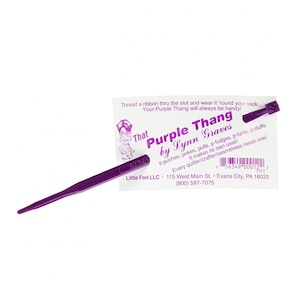 May include: Purple plastic tool called "That Purple Thang by Lynn Graves". It is used for pushing, poking, pulling, and stuffing. The tool is purple and has a slot for a ribbon. The card says "Every quilter/crafter/seamstress needs one!" and includes contact information for Little Foot LLC.