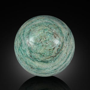 Pode incluir: Uma esfera verde e cinza feita de pedra polida. A esfera tem um padrão de redemoinho de verde claro e escuro.