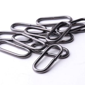 May include: A pile of black metal oval rings, likely used for attaching straps or other materials.