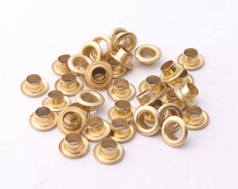May include: A pile of gold-colored metal eyelets, commonly used for crafts and leatherwork.