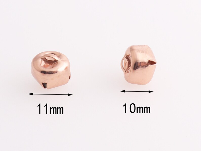 Może przedstawiać: Dwa dzwoneczki w kolorze r&oacute;żowego złota, jeden o wymiarach 11 mm, a drugi 10 mm.