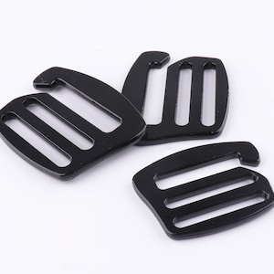 May include: Three black plastic slider buckles with three slots each. The buckles are designed to be used with straps or webbing.