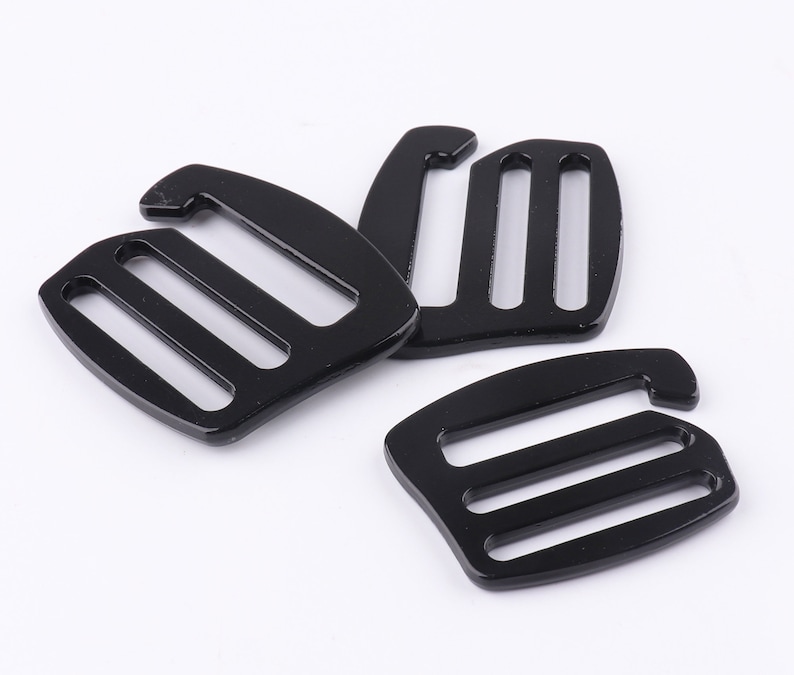 May include: Three black plastic slider buckles with three slots each. The buckles are designed to be used with straps or webbing.