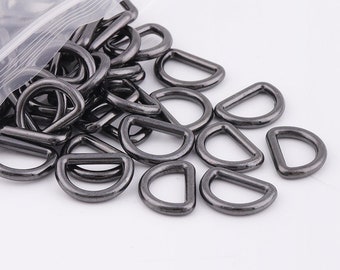 May include: A close-up of a pile of black metal D-rings. The rings are smooth and shiny, and they are all the same size.