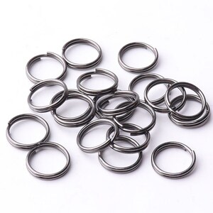 May include: A pile of black metal key rings. The key rings are all the same size and shape, and they are arranged in a random pattern.