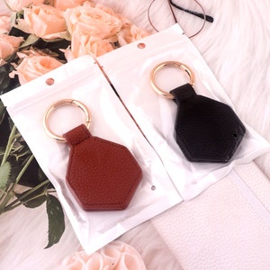 May include: Two keychains with gold rings and leather keychains. One keychain is brown leather and the other is black leather.