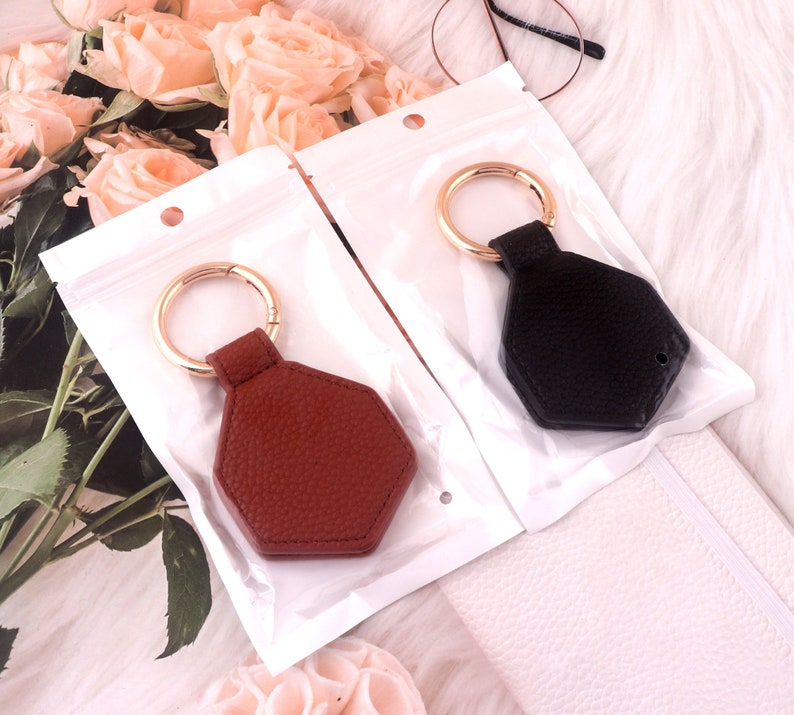 May include: Two keychains with gold rings and leather keychains. One keychain is brown leather and the other is black leather.