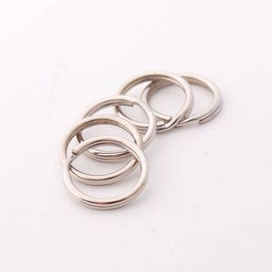 May include: A set of five silver key rings, all linked together. The rings are smooth and shiny.