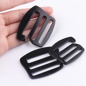 May include: Three black plastic buckle clips with three slots each. The clips are designed to be used for securing straps or cords.