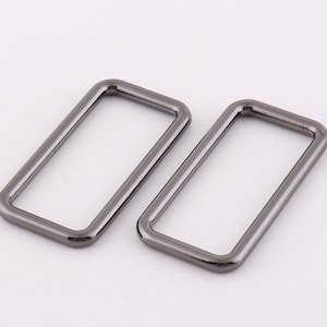 May include: Two silver-toned metal rectangular rings, each with a smooth, rounded edge. The rings are slightly different in size.