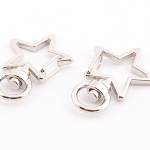 May include: Two silver star-shaped keyrings with a swivel clasp and a silver ring.