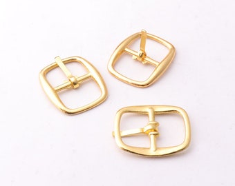 Puede incluir: Tres hebillas de cinturón de metal dorado. Cada hebilla tiene una forma rectangular con esquinas redondeadas y una barra central con un agujero para un cinturón.