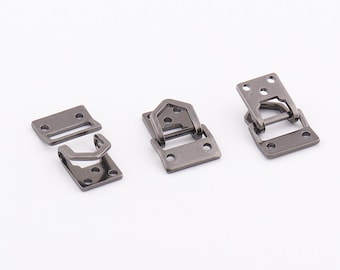 May include: Three silver-toned metal clasps, each with a different design. The clasps are used for attaching straps or belts to bags, clothing, or other items.