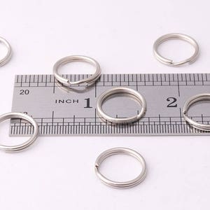 May include: Six silver key rings of varying sizes, measured against a ruler marked in inches.