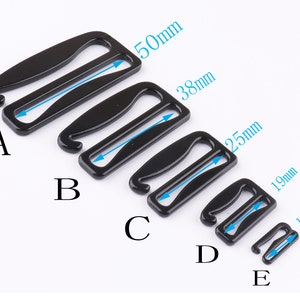 May include: Five black metal bra strap extenders in different sizes. The extenders are labeled A through E, with the largest being 50mm and the smallest being 13mm.