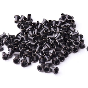 May include: A pile of black metal eyelets, used for reinforcing holes in fabric or leather.