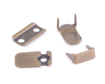 May include: Four antique gold metal clasps for attaching straps or buckles to fabric. The clasps have a rectangular shape with a small hole in the center.