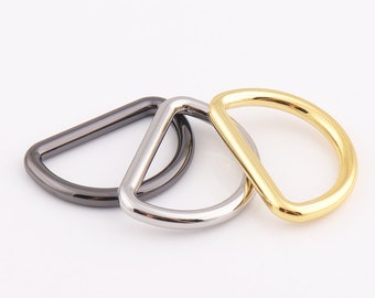 May include: Three metal D-rings in different finishes: black, silver, and gold. The rings are interlocked.