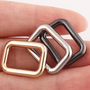 Puede incluir: Tres anillos en D de metal en oro, plata y negro.