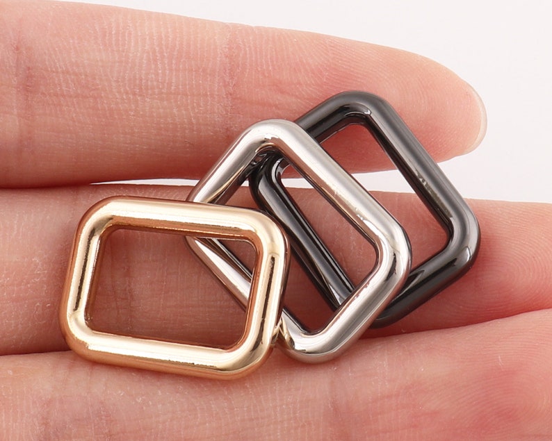 Puede incluir: Tres anillos en D de metal en oro, plata y negro.