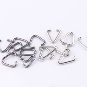 May include: A group of silver and black triangle jump rings. The jump rings are small and are used for jewellery making.