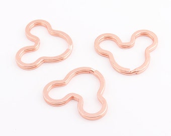 Op de afbeelding: Drie roosgoudkleurige sleutelhangers in de vorm van een cartoon muizenkop.