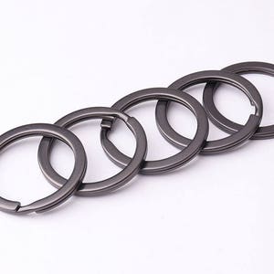 May include: Five gunmetal gray key rings linked together. The key rings are made of metal and have a smooth finish.