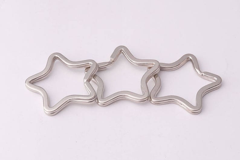 May include: Three silver star-shaped keychains linked together.