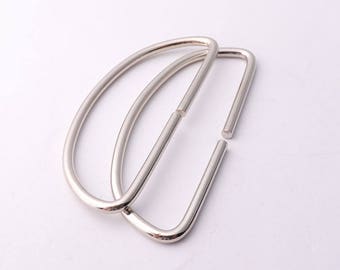 May include: Two silver metal D-ring handles for bags or purses. The rings are connected together.