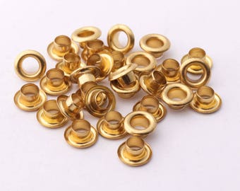 May include: A pile of gold-colored metal eyelets, also known as grommets, for crafts and DIY projects.