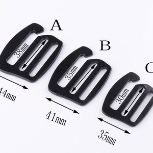 May include: Three black plastic slider buckles of different sizes. The largest buckle is 44 mm wide and 38 mm long. The middle buckle is 41 mm wide and 35 mm long. The smallest buckle is 35 mm wide and 30 mm long.