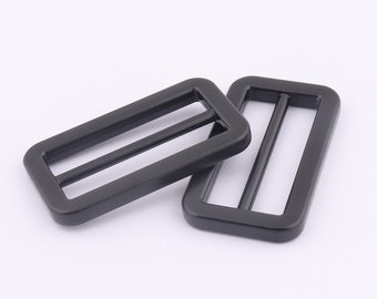 May include: Two black metal slider buckles. The buckles are rectangular with rounded corners and have a single slot in the center.