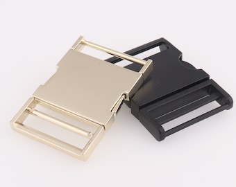 May include: Two plastic belt buckles, one gold and one black. The buckles are side by side and are both designed for a 1 inch wide belt.