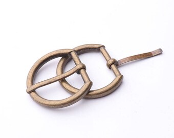May include: A pair of antique gold-toned metal belt buckles. The buckles are oval-shaped with a single prong closure.