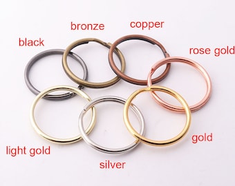 Op de afbeelding: Assortiment van sleutelringen in verschillende kleuren, waaronder zwart, brons, koper, rosé goud, licht goud, zilver en goud.