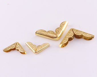 May include: Four gold metal corner protectors with a decorative design. The corner protectors are in various sizes.