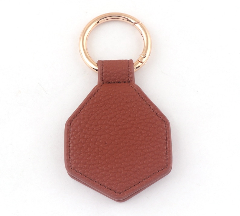 May include: A brown leather hexagon-shaped keychain with a gold metal ring.