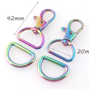 May include: Two iridescent rainbow-colored swivel clasps, each 42mm long, with matching D-rings, 20mm wide. The hardware is made of metal and has a colorful, oil-slick appearance. The clasps have a lobster claw design.
