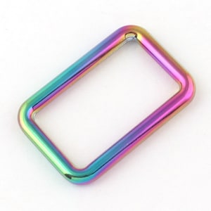 May include: A rainbow-colored metal rectangle ring, with a smooth, polished finish.