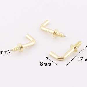May include: Two gold metal hooks with screws. The hooks are 1.7 inches long and 0.8 inches wide. The screws are 0.25 inches long.