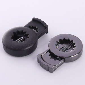 Puede incluir: Dos cierres metálicos con un mecanismo de resorte. Un cierre es negro y el otro es plateado.