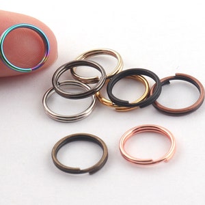 May include: Assortment of small metal key rings in various colors, including silver, gold, black, copper, and rainbow.