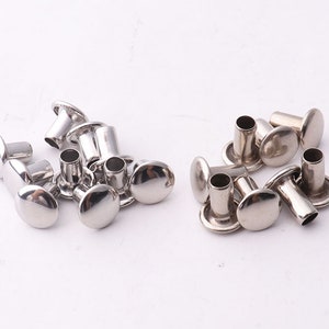 Peut inclure: Gros plan sur des rivets en métal argenté, également appelés rivets creux ou œillets. Ces rivets sont couramment utilisés pour l'artisanat du cuir, les vêtements et autres projets de bricolage.