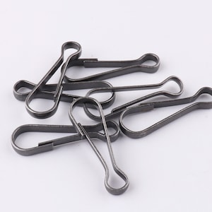 Pode incluir: Um grupo de oito fechos de gatilho de metal prateado. Os fechos estão em várias posições, alguns estão abertos e outros estão fechados.